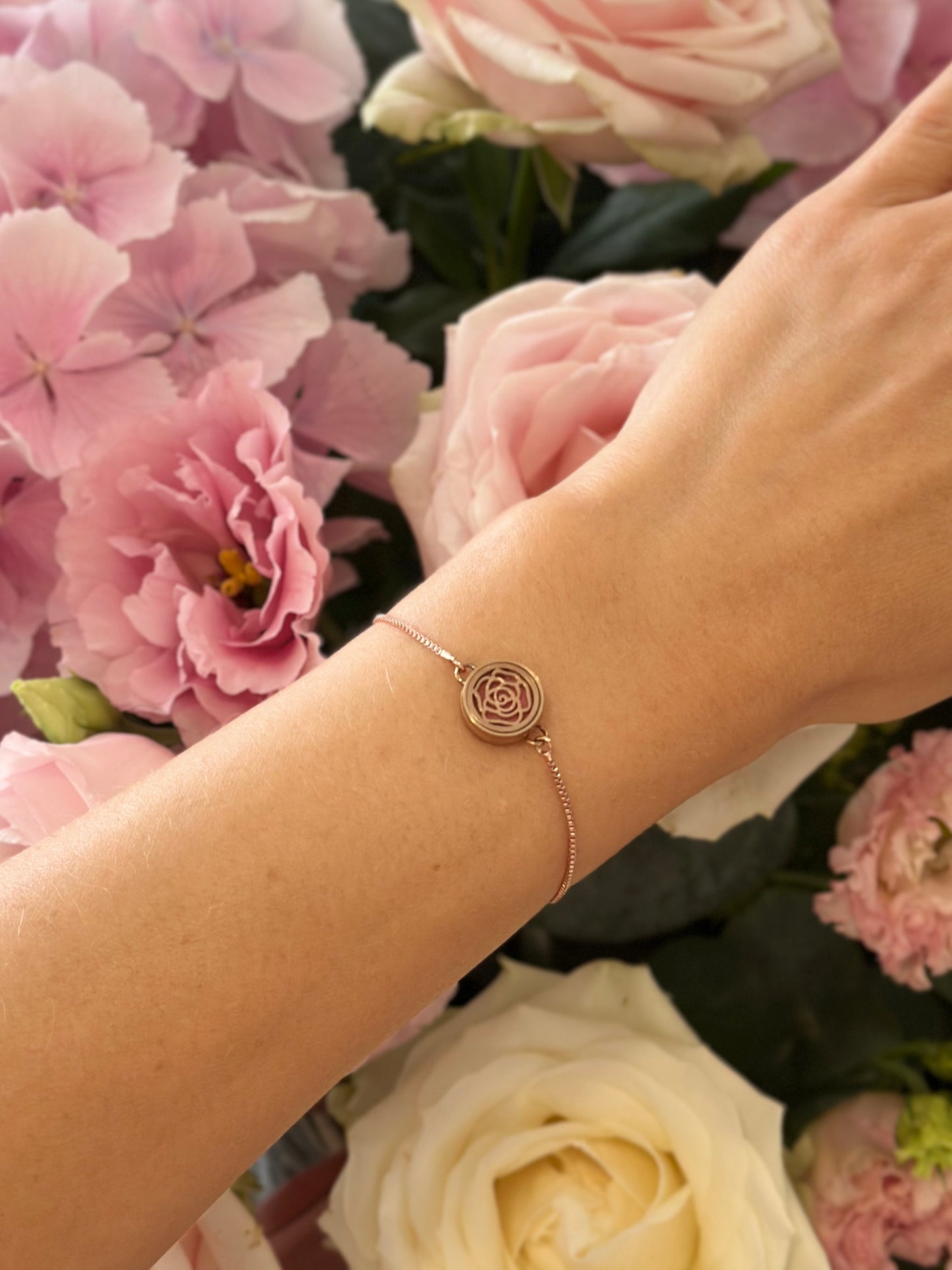 Luxury rose gold aromatherapy bracelet with roses background and rose oil diffuser creating a soft scent ritual for feminine energy