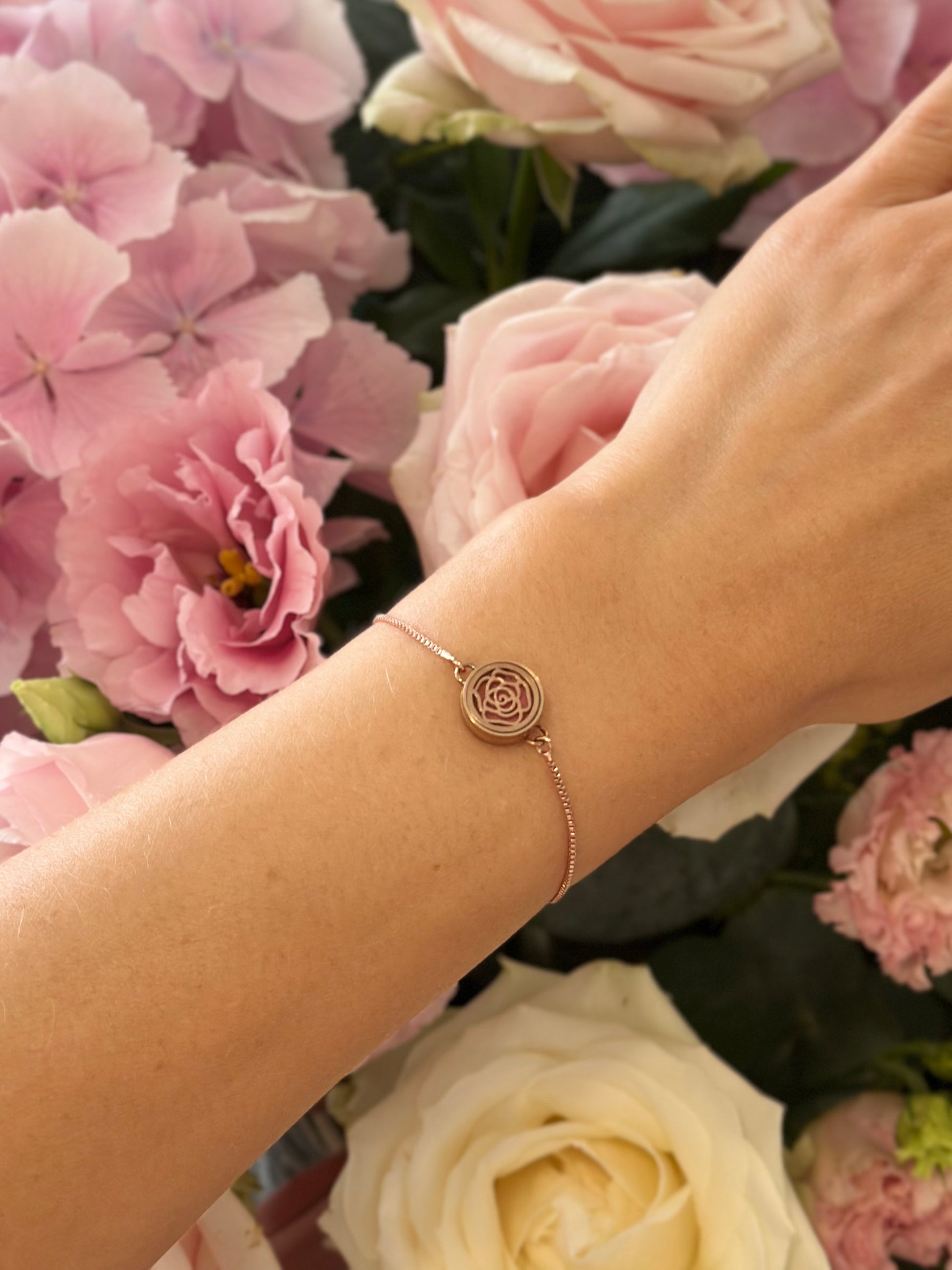 Luxury rose gold aromatherapy bracelet with roses background and rose oil diffuser creating a soft scent ritual for feminine energy